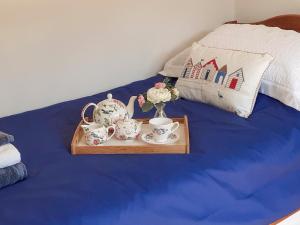 a tray with tea cups and a vase on a bed at Meadow Barn in Wool