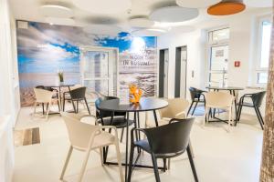 a dining room with tables and chairs and a mural at Jugendherberge Büsum in Büsum