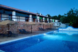 a swimming pool with chairs and umbrellas next to a building at Monte das Fontainhas in Pêra