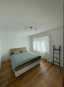 a white bedroom with a bed and a wooden floor at Appartamento Wyss in Bivio