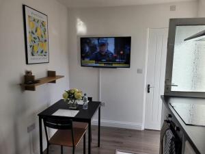 a living room with a table and a tv on the wall at Newly Built Studio Flat Sleeps 2 in Kent