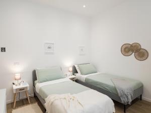 two beds in a room with white walls and lamps at Casa Design Con A/C e WiFi_[7 MINUTI CIAMPINO AEROPORTO] in Ciampino