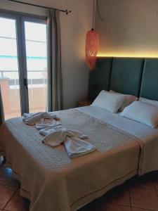 a bedroom with a bed with two robes on it at Ninos On The Beach Hotel in Roda
