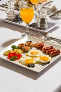 a plate of breakfast food on a table with a glass of orange juice at Abba Hotel in Belgrade