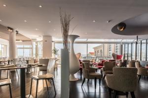 un restaurant avec des tables et des chaises et une salle avec des fenêtres dans l'établissement Côté Thalasso Hôtel & Spa Marin, à Banyuls-sur-Mer