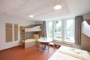 Cette chambre comprend une table et des lits superposés. dans l'établissement Jugendherberge Büsum, à Büsum