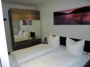 eine weiße Couch in einem Schlafzimmer mit Spiegel in der Unterkunft Residenz am Balmer See - BS 07 mit Wellnessbereich in Balm