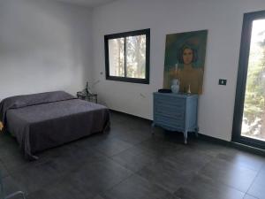 Dar el Koudia的住宿－The Green Blue House，卧室配有一张床,墙上挂有绘画作品