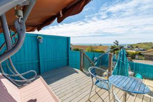 a deck with two chairs and a table and a table and chairs at Fairwinds,Bigbury on sea ,Three-bed Beach House in Bigbury on Sea