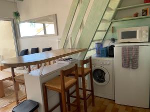 a small kitchen with a table and a washing machine at Appartement calme vue sur l'hérault et la mer in Agde +2 photos