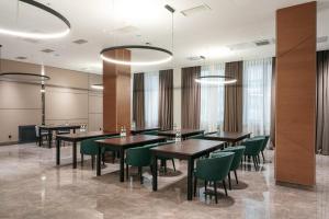 uma sala de jantar com mesas e cadeiras verdes em Raavah Aparthotel em Almaty