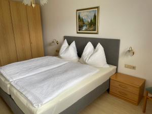 um quarto com uma cama com lençóis e travesseiros brancos em Am Randersberg - Wohnung Nr 2 em Grossgmain