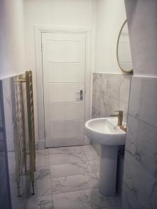 Baño blanco con lavabo y espejo en Sweeney Stays, Cadzow Apartment, en Hamilton