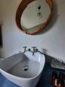 lavabo con espejo de madera encima en Nel's Cottage, a private and peaceful cottage, en Benoni