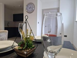 a table with two wine glasses and a vase with flowers at Beautiful and Spacious 2-Bed Apartment: Home Away From Home in South Benfleet