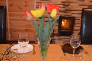 a vase of flowers on a table with two wine glasses at Country House v Kleynikah in Brest