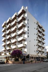 a white building with balconies on the side of a street at Apartamentos El Moro in San Antonio