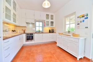 a kitchen with white cabinets and a orange tile floor at VILLA MONTE PARDAL w/ Heated Pool in Natural Park in Moncarapacho