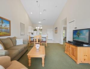 un salon avec un canapé, une télévision et une table dans l'établissement Lely Greenlinks Top Floor - on Golf Course, Minutes from Beaches, Downtown!, à Naples