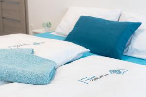 a bed with white sheets and blue pillows at Türkiz apartman in Kőszeg