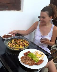 una mujer sentada en una mesa con platos de comida en Dihini Villa, en Unawatuna