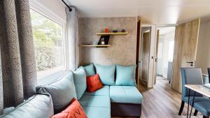 a living room with a blue couch and a window at Camping Officiel Siblu La Réserve in Gastes