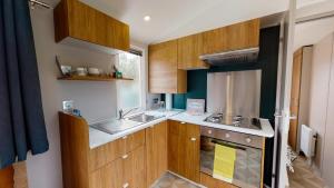 a kitchen with wooden cabinets and a sink at Camping Officiel Siblu La Réserve in Gastes