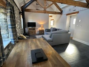 a living room with a couch and a tv at Beudy Howel - A beautiful converted barn close to the coast in Llansadurnen