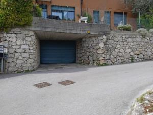 a garage with a blue door and a stone wall at L'angolo di pace e relax del lago di Garda in Riva del Garda