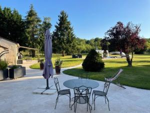 eine Terrasse mit einem Tisch, Stühlen und einem Sonnenschirm in der Unterkunft GITE ROMANTIQUE in Cléré-les-Pins