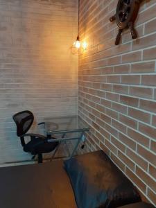 uma mesa de vidro e uma cadeira num quarto com uma parede de tijolos em Condominio Costa do Sol Praia - 600mt da praia em Bertioga