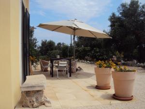 um pátio com uma mesa, um guarda-chuva e flores em DEPANDANCE CON PISCINA IN VILLA VICINO PORTO CESAREO em Copertino