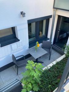a patio with two chairs and a table with a flower on it at Schickes Apartment in Düsseldorf- Flehe in Düsseldorf