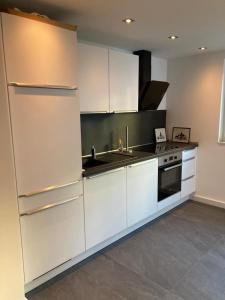 a kitchen with white cabinets and a sink and a stove at Schickes Apartment in Düsseldorf- Flehe in Düsseldorf