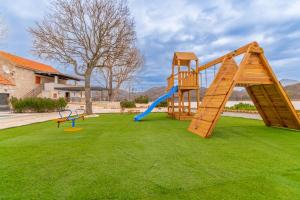 un parque infantil con 2 equipos de juego en un césped en Villa Biokovska, en Podgora