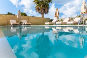 a swimming pool with chairs and umbrellas at My Corfu Luxury Villa with private pool at Sidari in Sidari