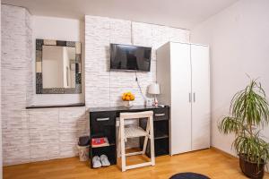 Zimmer mit einem Schreibtisch und einem TV an einer Backsteinwand in der Unterkunft Paris Night in Niš