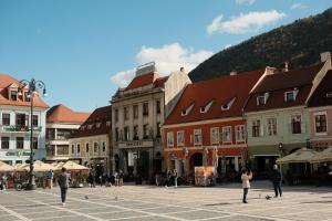 a group of people walking around a town with buildings at ComFee Apartment - Ultracentral in Braşov