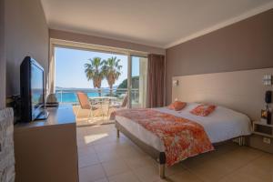 um quarto com uma cama e vista para o oceano em Hotel Le Grand Pavois em Le Lavandou