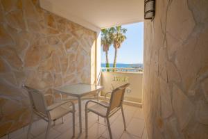 una mesa y sillas en una habitación con una pared de piedra en Hotel Le Grand Pavois en Le Lavandou