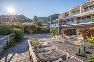 a resort with a deck with chairs and tables at Hotel Le Grand Pavois in Le Lavandou