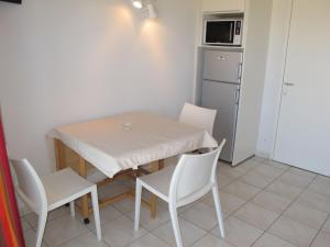 una pequeña cocina con mesa, sillas y nevera. en Apartment Résidence Belle Dune - BPL331 by Interhome, en Biscarrosse-Plage