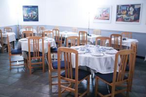 un comedor con mesas y sillas con manteles blancos en Hotel Montañés en Suances