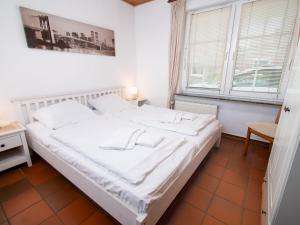 ein großes weißes Bett in einem Zimmer mit zwei Fenstern in der Unterkunft Apartment Nordwind by Interhome in Norddeich