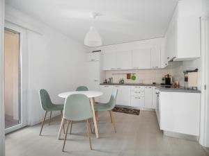 cocina con armarios blancos, mesa y sillas en Caslano City Apartments en Caslano