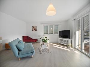 un soggiorno con sedia blu e TV di Caslano City Apartments a Caslano