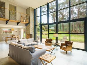 una sala de estar con grandes ventanas de cristal y muebles. en Holiday Home du bois du Kador by Interhome, en Morgat