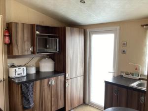 a small kitchen with a sink and a microwave at Luxury caravan at Seton Sands in Port Seton
