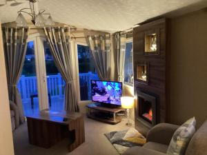 ein Wohnzimmer mit einem TV und einem Kamin in der Unterkunft Luxury caravan at Seton Sands in Port Seton