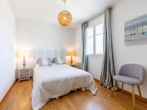 ein weißes Schlafzimmer mit einem Bett und einem Stuhl in der Unterkunft Apartment Les Hautes Folies-5 by Interhome in Saint-Palais-sur-Mer